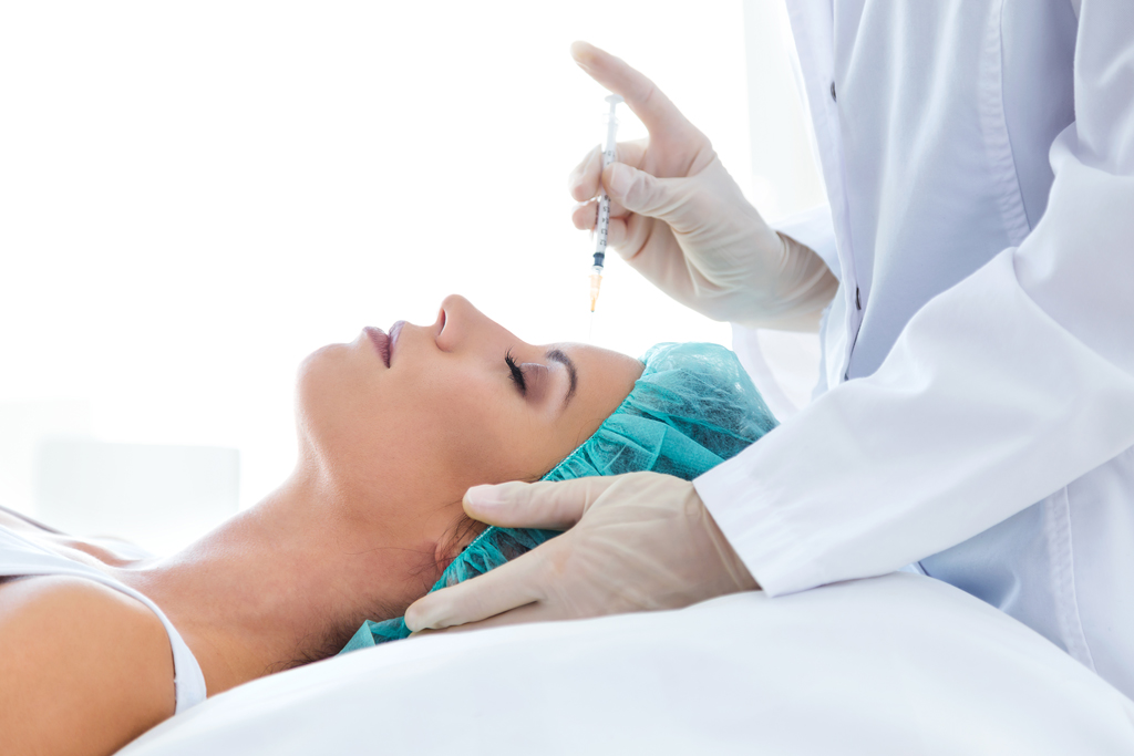 Portrait of beautiful young woman getting botox cosmetic injection in her face.
